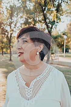 Close up portrait of lovely hispanic middle aged woman in the park