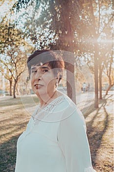Close up portrait of a hispanic senior woman in the park at sunset
