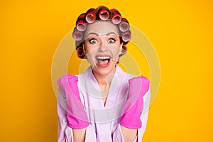 Close-up portrait of lovely overjoyed cheerful housekeeper wearing curlers celebrating great news isolated bright yellow