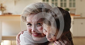 Close up portrait loving grandmother and little granddaughter hugging indoor