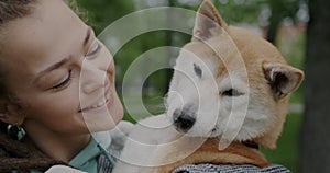 Close-up portrait of loving woman kissing cute shiba inu dog expressing love and happinness outdoors on summer day