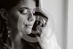 Close-up portrait of a luxurious bride in a wedding dress in the morning in her interior