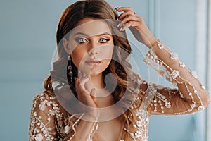 Close-up portrait of a luxurious bride in a wedding dress in the morning in her interior