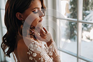 Close-up portrait of a luxurious bride in a wedding dress in the morning in her interior