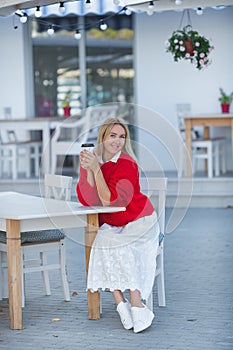 Close-up portrait of magnificent caucasian girl lady wearing red sweater and white skirt. Lovable long-haired blonde woman