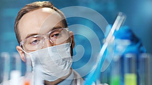 Close-up portrait of male chemic doctor wearing protective mask working on vaccine from virus