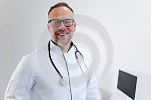 Close-up portrait of a male doctor with a stethoscope around his neck and white medical coat.