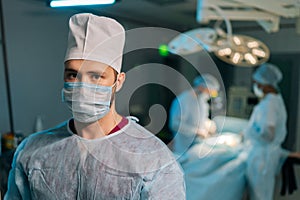 Close-up portrait of male doctor in surgical uniforms and masks standing posing looking at camera in operating room
