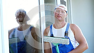 Close-up, portrait of a male worker of cleaning service, in blue overalls and in a cap, blaser, with a special mop for