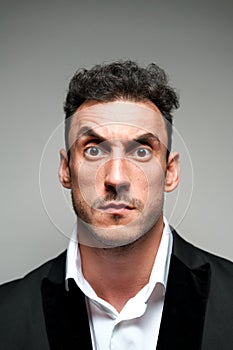 Close up portrait of a man 30-34 years old in a white shirt and a black jacket on a gray background.