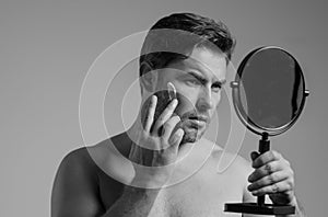 Close up portrait of man 40s applying cream on face. Handsome serious man enjoy fresh perfect skin, applying cream