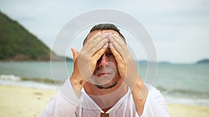 Close-up portrait man apply sun cream protection lotion, looking at camera. Caring man on beach near sea smearing