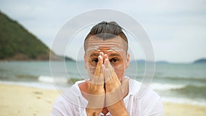 Close-up portrait man apply sun cream protection lotion, looking at camera. Funny man on beach near sea smearing
