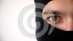 Close-up portrait of a man in a black balaclava. Brown eyes close up.