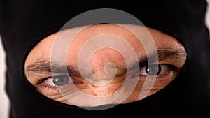 Close-up portrait of a man in a black balaclava. Brown eyes close up.