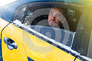 Close-up portrait of a man, a car passenger looking out the open window in winter