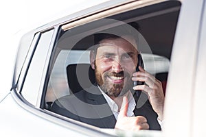 Close-up portrait of a man, a car passenger talking on the phone and looking out the open window