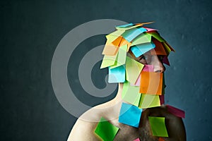 Close up portrait of man covered with colorful sticky notes all over his face and body looking to camera