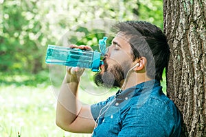 Close up portrait of a man drinking water from a bottle outside