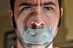 Close up portrait of a man with duct tape over his mouth