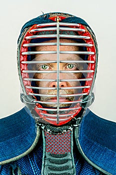 Close up portrait of man in kendo helmet, kendoka studio shot on white.