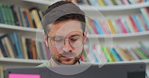 Close up portrait man student preparing exam and learning lessons in library, making research on laptop and browse