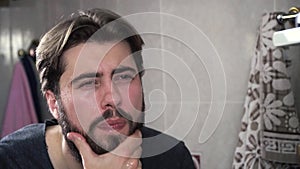 Close-up portrait of man washing his face with water. Man with thick beard washes in bathroom. Morning routine washing