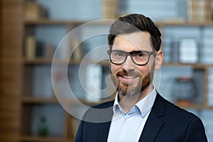 Close-up portrait of mature adult experienced businessman, boss smiling and looking at camera wearing glasses and