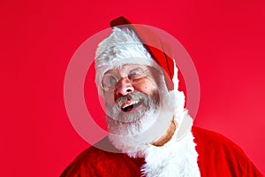 Close up portrait of mature man with long grey beard in glasses dressed in Santa Claus festive costume cheerful smiling