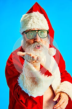 Close up portrait of mature man with long thick white beard, Santa Claus in fashion sunglasses make air kiss against