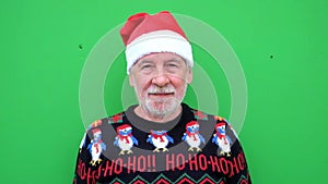 Close up and portrait of mature and old man or senior smiling and looking at the camera wearing christmas clothes and hat with gre