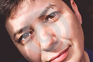 Close-up, portrait of a middle aged brunette woman with piercings in the rays of the sun