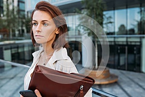 Close-up portrait of a middle-aged businesswoman holding a leather folder