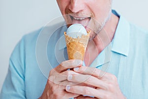 Close-up portrait of middle-aged man eating cone lavender ice cream.