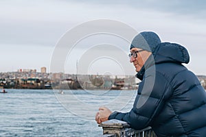 Close-up portrait of middle-aged man wearing glasses,standing on the embankment of the river and looking into the