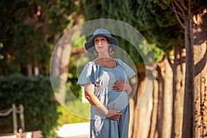 Close up portrait middle aged pregnant woman in pine forest. Concept of travel during pregnancy
