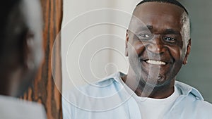 Close up portrait mirror reflection happy senior retired african adult american man with bristle smiling wink himself