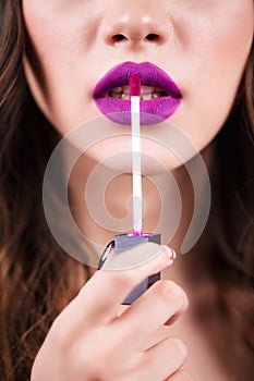 Close up portrait model applying purple lipstick.. Professional fashion make up.