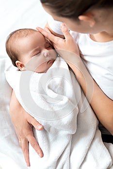 close-up portrait of mom with newborn baby on white background copy space. Young cute caucasian woman black haired