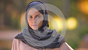 Close-up portrait of Muslim girl in hijab watching into camera , waving her head to disagree.