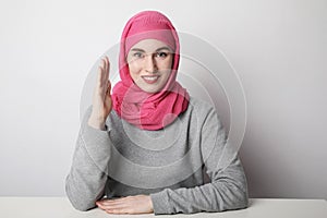 Close-up portrait of a muslim young woman wearing a hijab and putting hand up. Women rights concept.