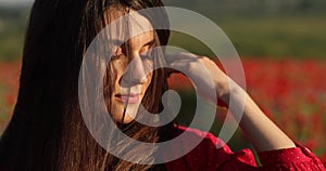 Close up portrait of nature beauty woman in the middle of the field of poppies. Her perfect brunette long hair