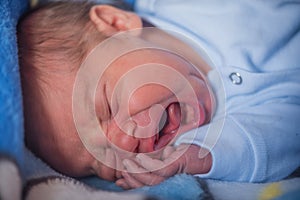 Close up portrait of a newborn baby boy crying in the bed