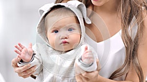 Close-up portrait of newborn cute baby posing sitting on mother knee playing clapping hand