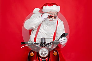 Close-up portrait of nice bearded shocked worried funny funky Santa wearing cap hat sitting on motor bike using cell