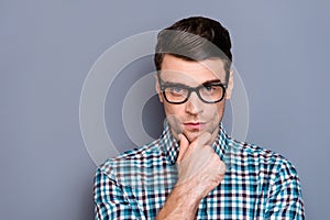 Close-up portrait of nice well-groomed handsome attractive minded guy wearing checked shirt touching chin thinking