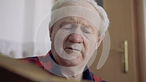 Close up portrait of old handsome, emotionally man reads the book