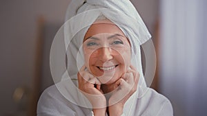 Close up portrait old middle-aged mature senior Caucasian smiling woman face lady in bath robe with towel on head with
