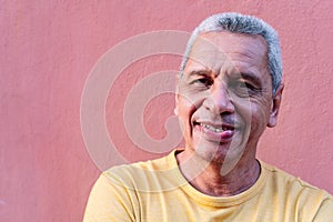 Close up portrait older Hispanic man leaning against wall and staring