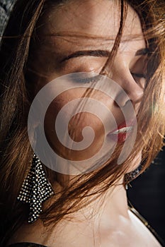 Close-up portrait plus size model in a gold blouse and black jeans leaned on a brick loft wall.